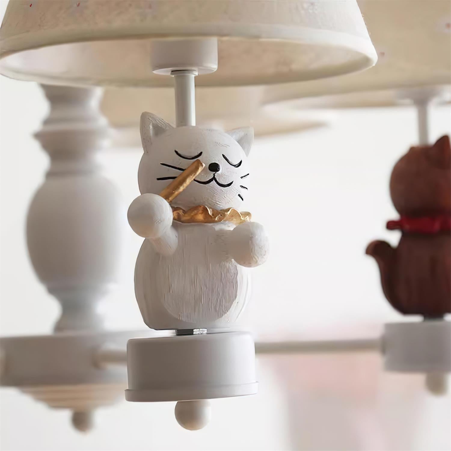Cat figurine finial holding a fish-like piece on a hanging chandelier base