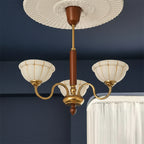 Gold 5-light chandelier with curved arms, off-white glass shades, brown top cap