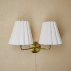 Double-head fabric wall lamp with two pleated white shades and gold circular wall mount