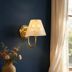 Gold conical capiz shell wall sconce with curved arm and bell-shaped shade