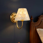 Gold conical capiz shell wall sconce with curved arm and round wall mount base