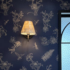 Gold conical capiz shell wall sconce with lit shade and slim vertical support