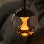 Close-up of hourglass globe pendant light with clear glass and warm amber interior
