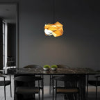 Pair of light wood ribbon pendant lamps with overlapping shades and warm glowing light.