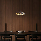 Marble pendant light hanging over dining table; gray and amber veined disc shade