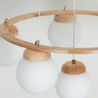 Close-up of wooden ring and frosted glass globe shades with brass caps on hanging cords