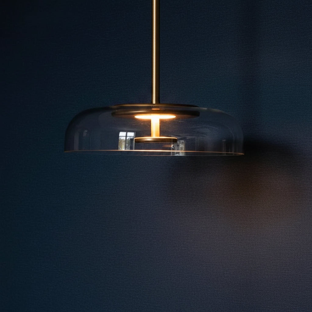 Smoked glass dome pendant light with brass top cap and warm glowing bulb