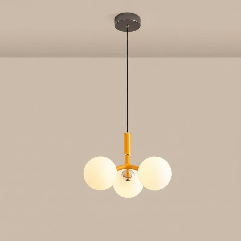 Globe pendant light with three white glass spheres, black canopy, and amber tube
