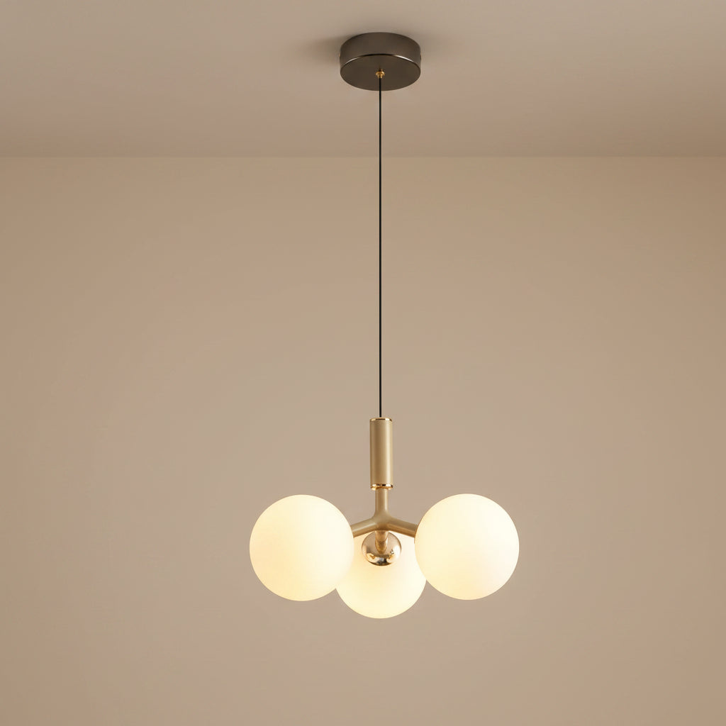 Globe pendant light with three white glass spheres and brass central stem, black canopy