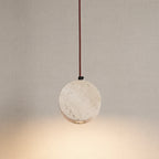 Round travertine disc pendant light with copper cord and warm downlight
