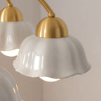Close-up of white scalloped shade with gold cap and soft glowing bulb.