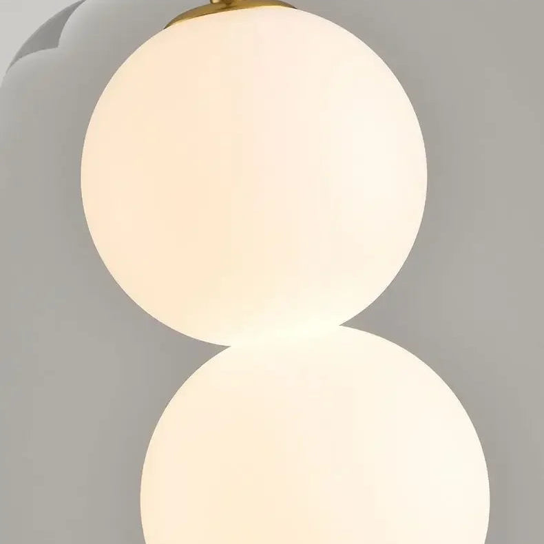 Close-up of stacked opal glass globe shades with gold connector