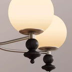 Close-up: bronze globe chandelier arms with white shades and dark spherical finials