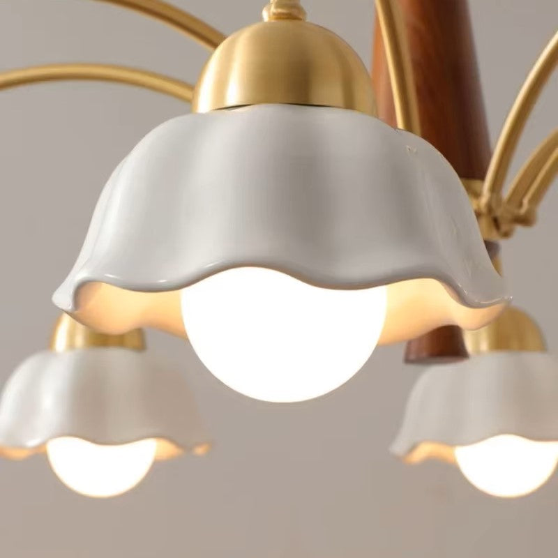 Close-up of white scalloped glass shade on gold socket with warm light glowing below.