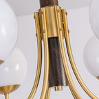 Close-up of gold globe chandelier metal canopy, dark brown stem, and curved brass arms