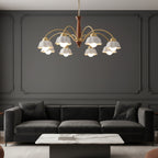 Multi-arm chandelier featuring gold curves, brown center, and white scalloped shades overhead.
