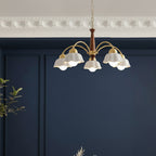 Gold-and-brown chandelier with multiple curved arms and white scalloped shades facing down.
