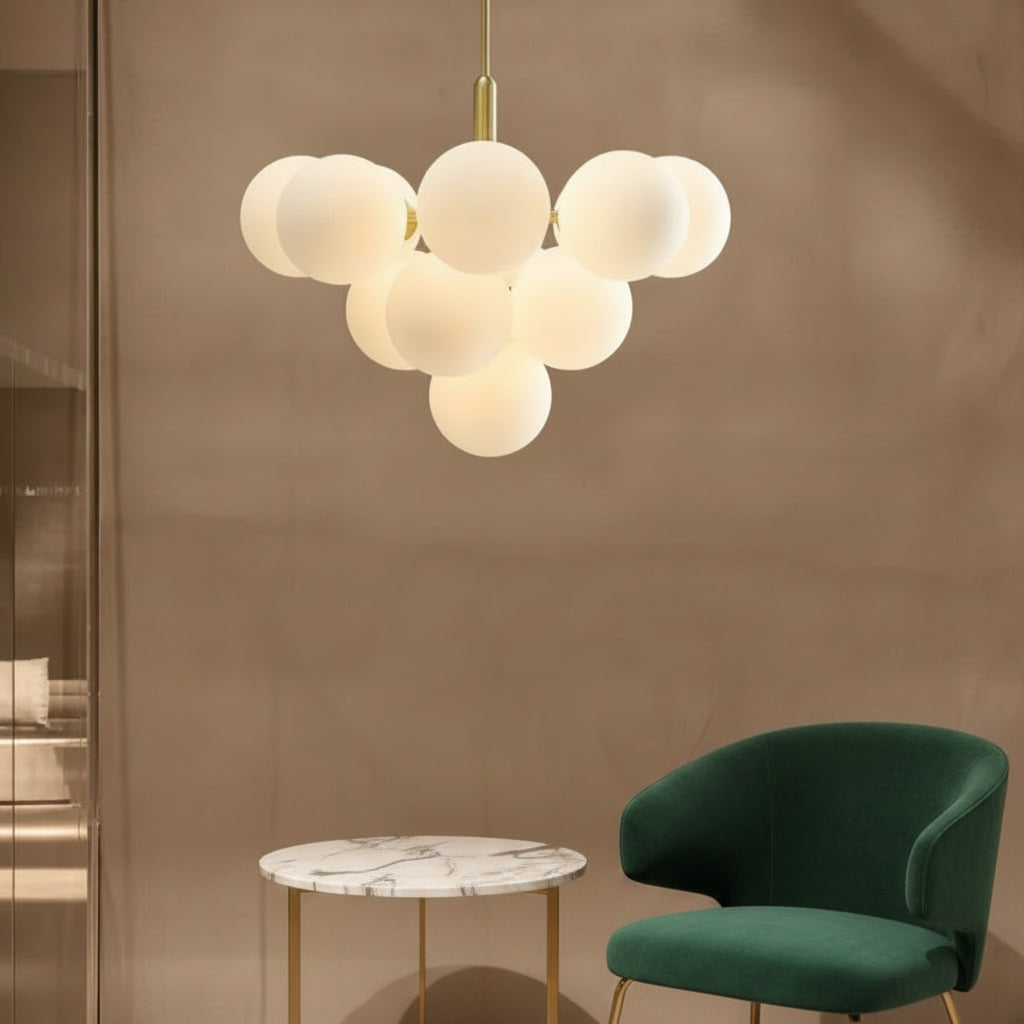 Frosted white bubble globe chandelier with brushed gold stem and canopy above seating