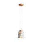 Terrazzo cylindrical pendant light with wooden top plate and speckled drum shade.