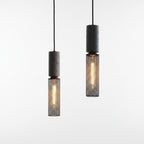 Tubular cage pendant light with dark speckled cylinder housing and warm glowing filament bulb