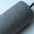 Close-up of dark speckled cylindrical pendant housing with rough textured finish