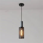 Tubular cage pendant light with dark speckled cylinder top and warm glowing filament bulb