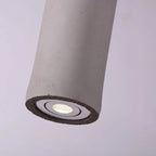 Tubular pendant light with speckled gray concrete housing and recessed glowing bulb