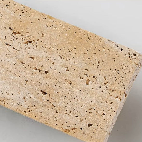 Close-up of rectangular travertine wall light with speckled stone texture