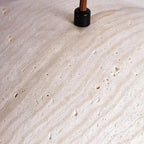 Travertine surface of pendant light, speckled stone finish near hanging cord and socket