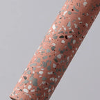 Red speckled cylinder pendant light with black cord.
