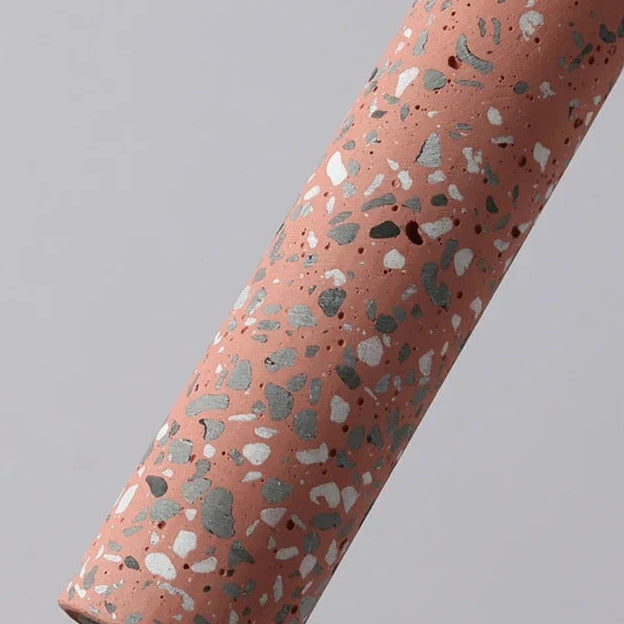 Red speckled cylinder pendant light with black cord.