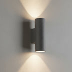Concrete wall light with cylindrical shade, dark finish, warm glow from the lamp