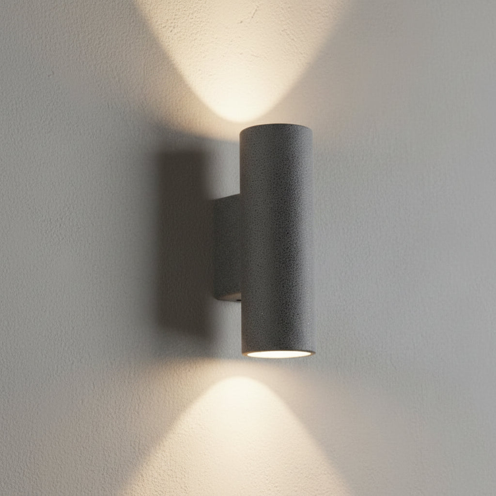 Concrete wall light with cylindrical shade, dark finish, warm glow from the lamp