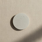 Round concrete wall light with speckled light-gray disc on wall