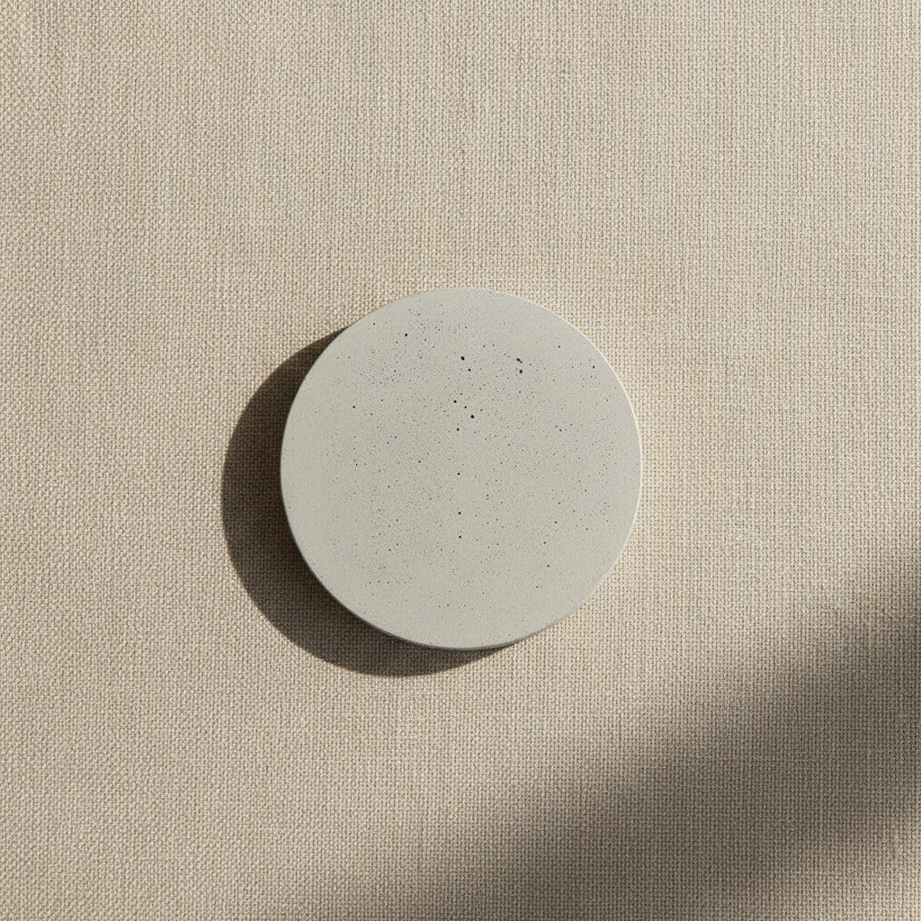 Round concrete wall light with speckled light-gray disc on wall