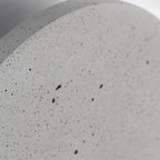Speckled concrete light-gray round wall light face, close-up