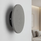 Round concrete wall light with light-gray front and black side mount