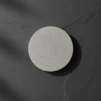 Round concrete wall light with speckled light-gray disc, front view