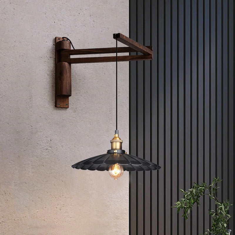 Wall-mounted pendant light with dark wood arm, black scalloped shade, and exposed bulb