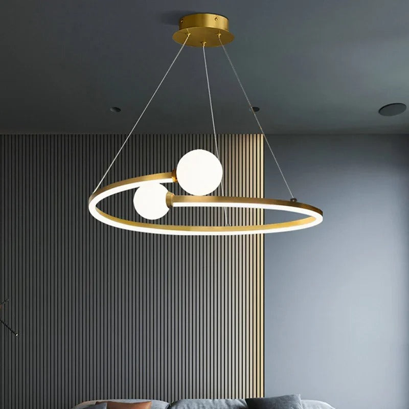 Gold ring LED chandelier with three white globe lights against a striped wall panel