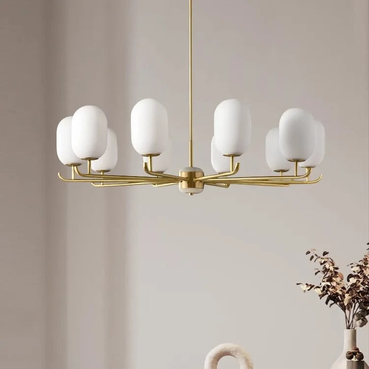 Gold multi-arm chandelier with five white glass globe shades and curved mounting bar