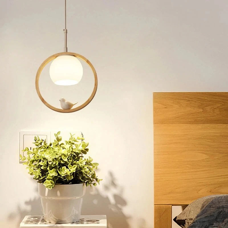 Hanging wooden ring bird pendant light with glowing dome bulb.