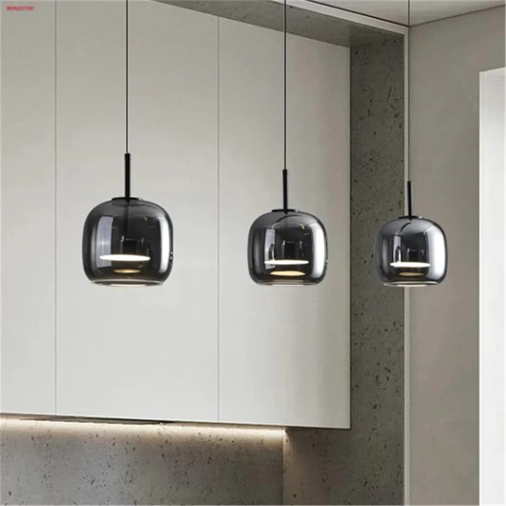Three smoked glass cube pendant lights hanging against a light wall