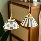 Pair of ceramic conical pendant lights: blue floral and blue stripe shades with brass tops