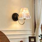 Capiz shell conical wall light with black backplate and warm glow capiz shade
