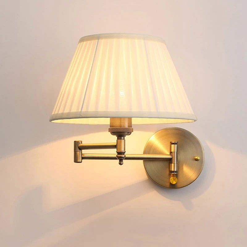 Brass wall sconce with swing arm, fabric drum shade, and round backplate