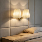 Gold-tone twin wall light with two pleated shades mounted on the wall