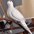 White bird figurine perched on dark metal chandelier frame with hemp rope