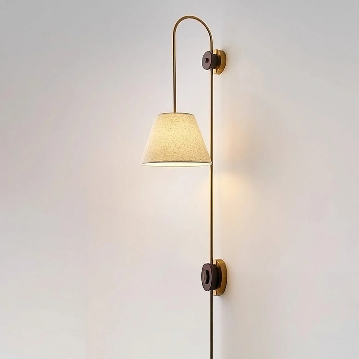 Wall-mounted swan neck light with tapered beige fabric shade and brass finish