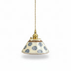Ceramic conical pendant light with blue floral pattern shade and brass cord mount